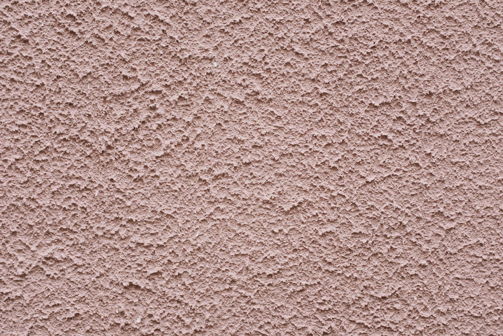 Simple background of uneven stucco pink wall surface of modern building in city
